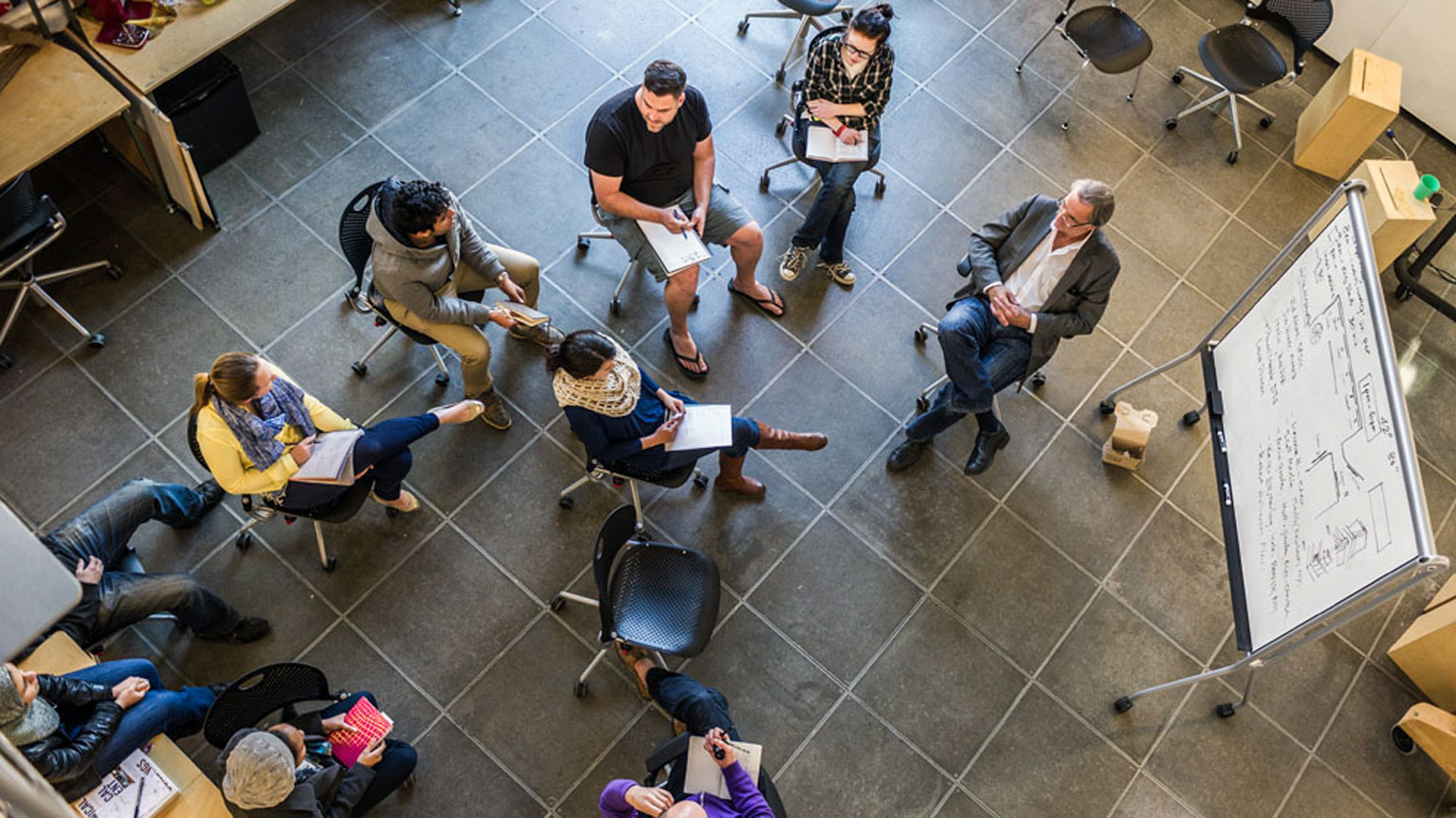 Students sit in a semicircle around a Design Bloc professor in conversation during Design Methods class. 