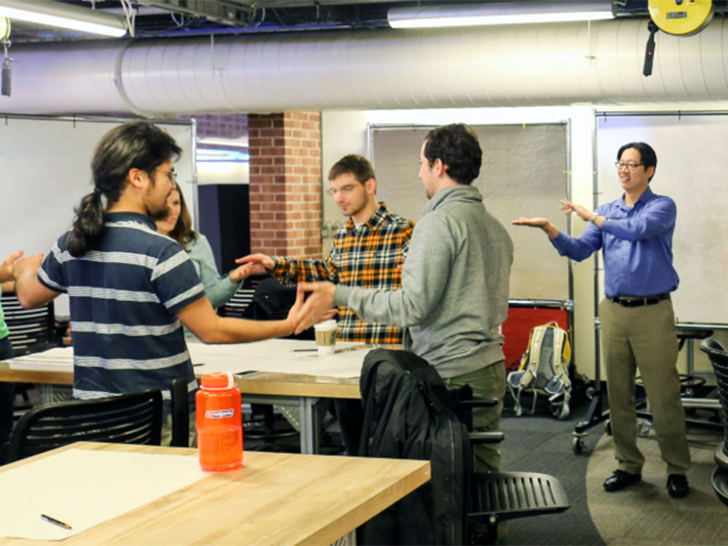 Coworkers take part in an improv-inspired warmup activity before learning how to brainstorm ideas in a Design Bloc workshop.  